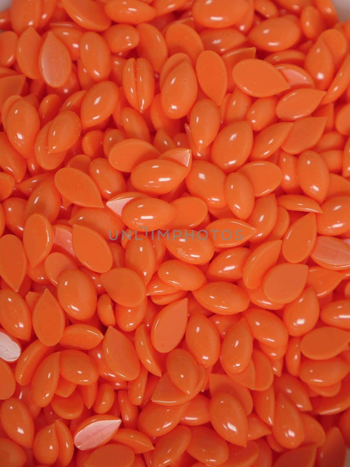 Background orange wax in depilatory granules close-up, vertical