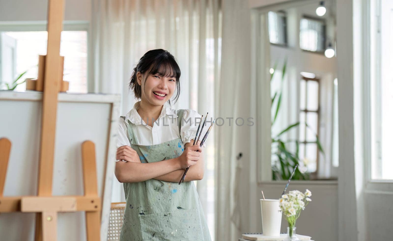 Portrait of a young female artist working on an abstract acrylic canvas painting in an art painting studio..