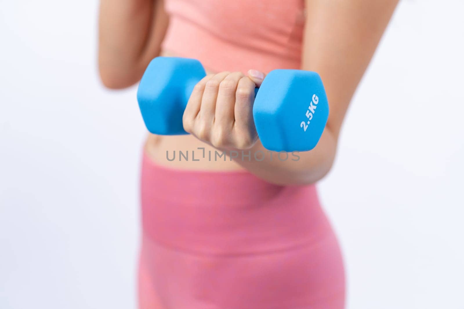 Vigorous energetic woman doing dumbbell weight lifting exercise on isolated background. Young athletic asian woman strength and endurance training session as body workout routine.