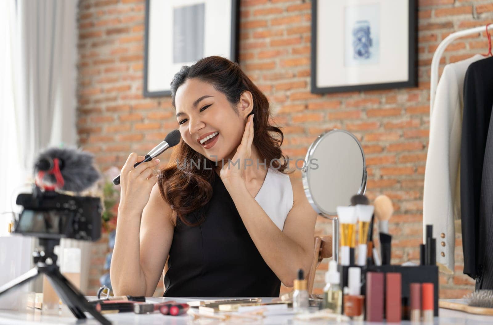 Asian Woman influencer shoot live streaming vlog video review makeup uttermost social media or blog. Happy young girl with cosmetics studio lighting for marketing recording session broadcasting online