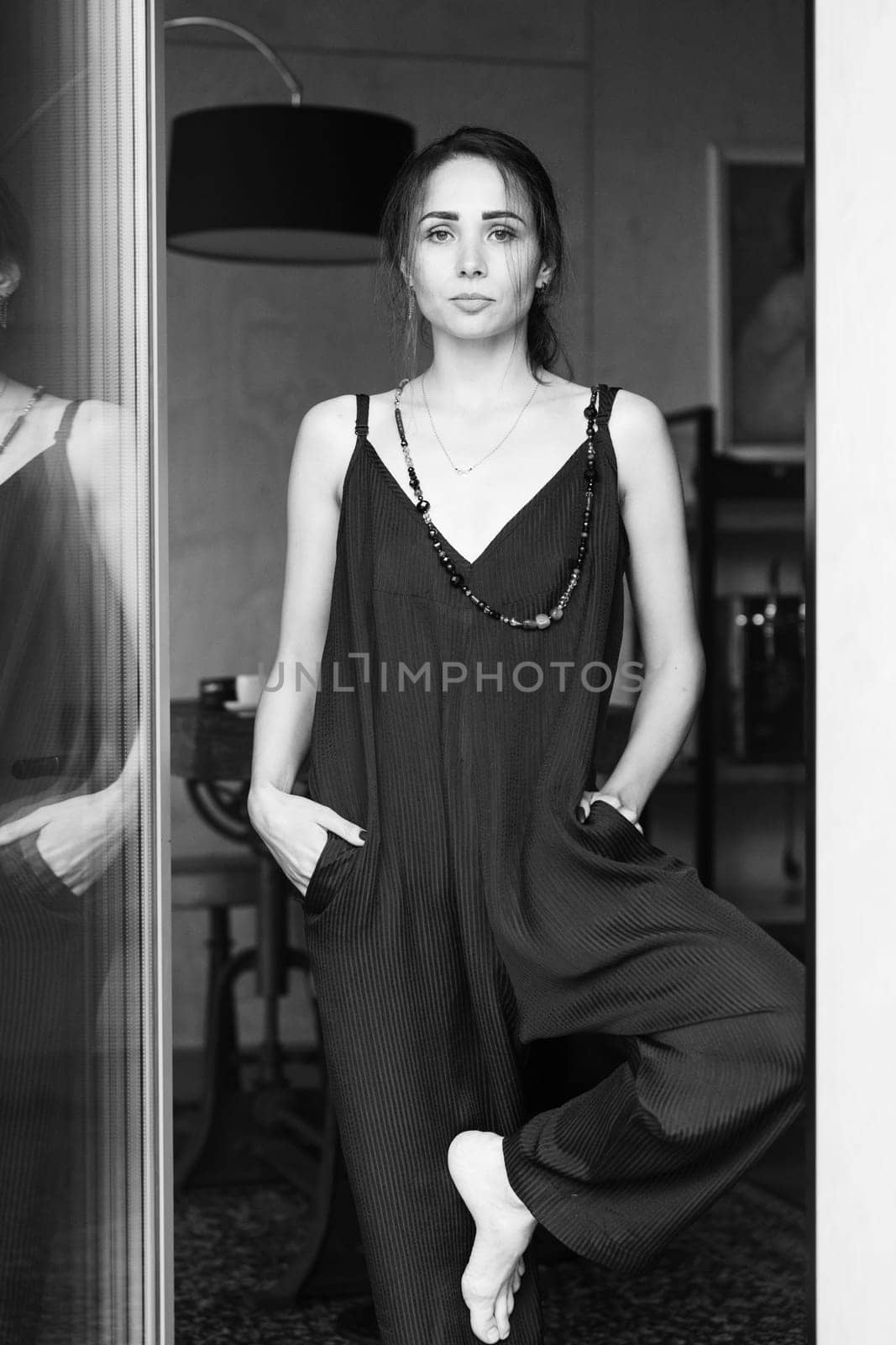 Summer fashion conception: Fashionable woman wearing jumpsuit, posing in stylish boho interior