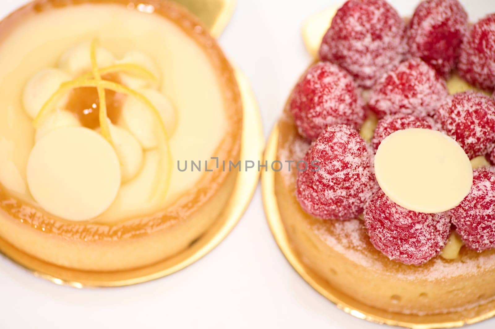 Close-up. View from above of delicious traditional French desserts - a lemon and raspberry meringue cake and tartlet on a white plate.