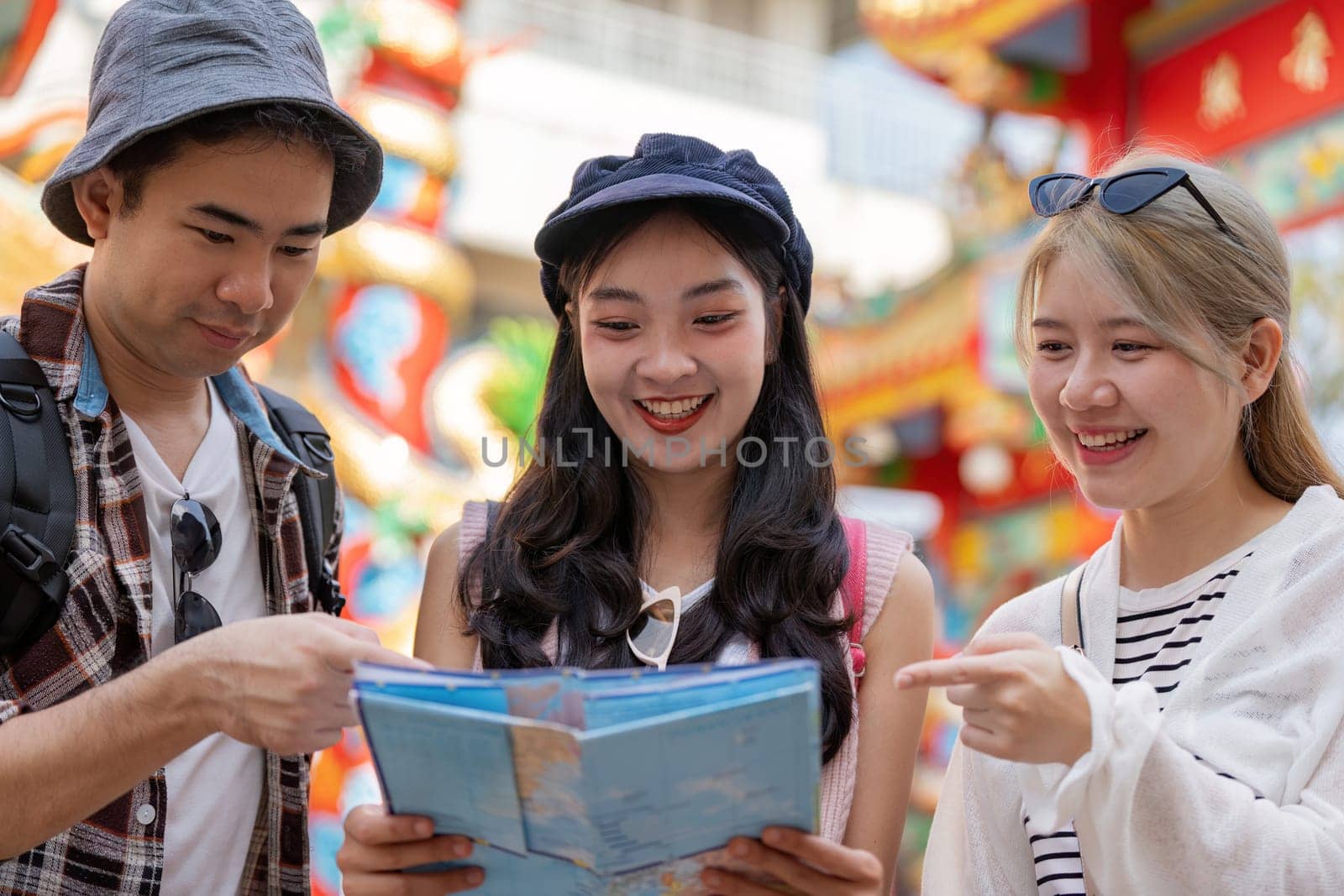 Three friends explore a vibrant market sharing laughter and navigating with a map capturing the essence of travel.