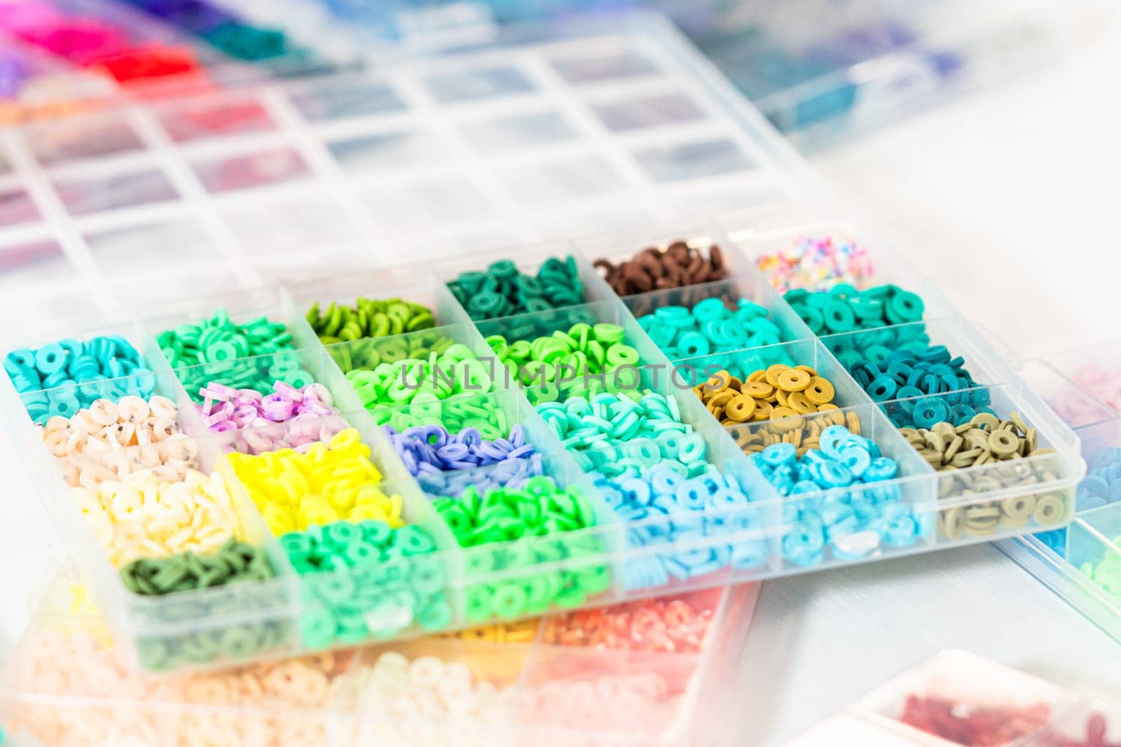 Assorted clay bead boxes neatly arranged on a white table, awaiting a creative kids' craft project.