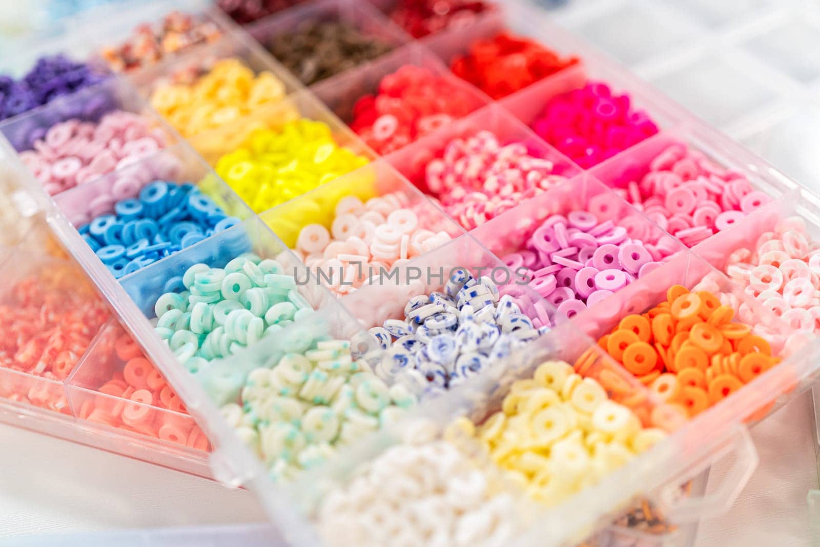 Assorted clay bead boxes neatly arranged on a white table, awaiting a creative kids' craft project.