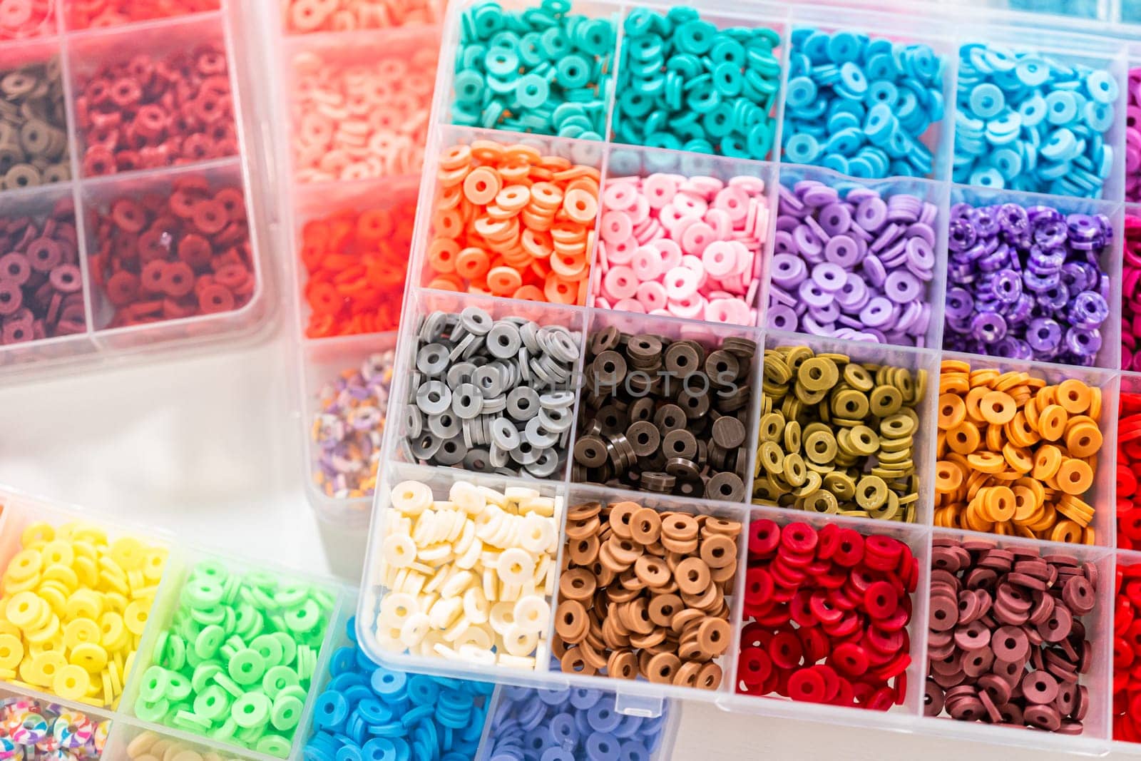 Assorted clay bead boxes neatly arranged on a white table, awaiting a creative kids' craft project.