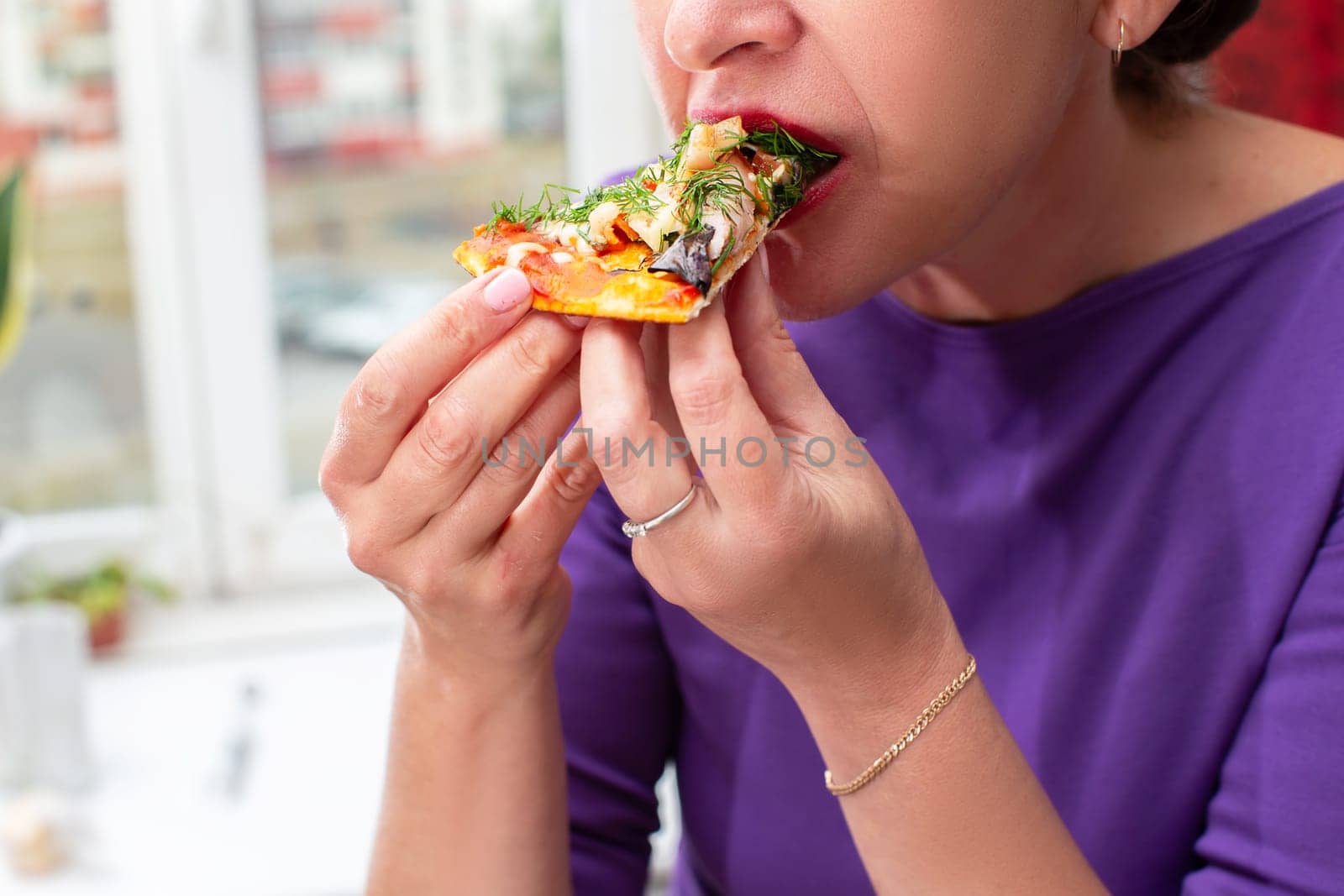 Woman's hands hold a piece of pizza in her hand.Eating pizza