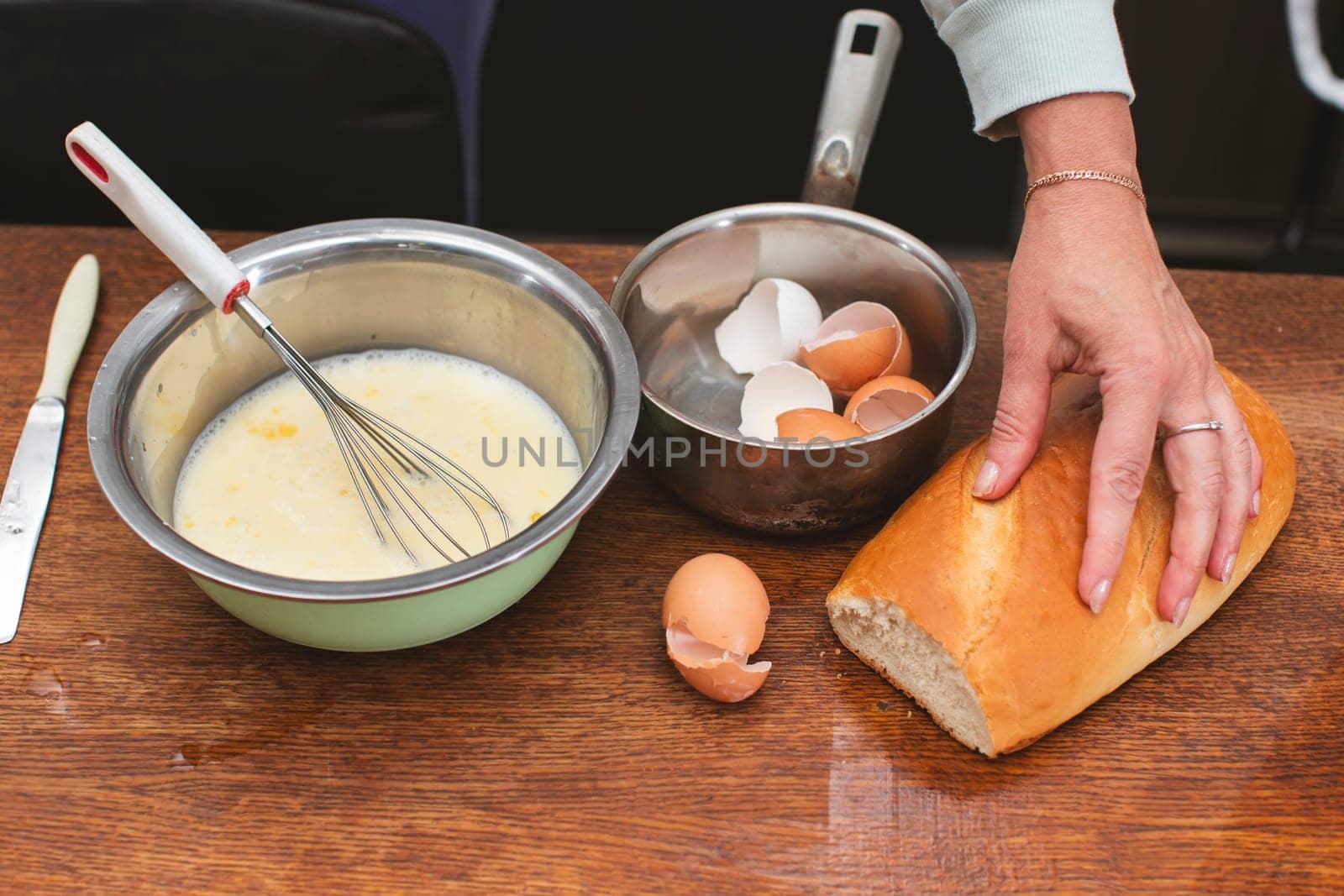 In a bowl there is a mixture for making an omelet and on the shells for eggs and a loaf. Prepare breakfast.