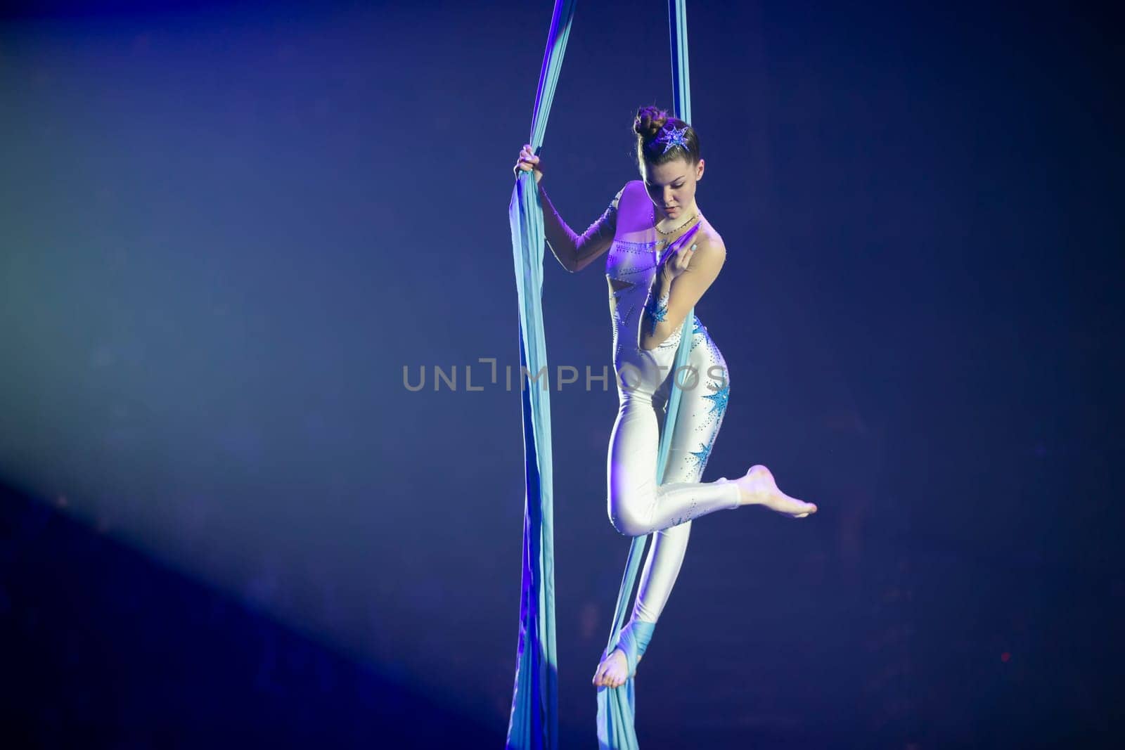 Performance by a circus acrobat artist. Girls perform aerial acrobatic elements on fabric.