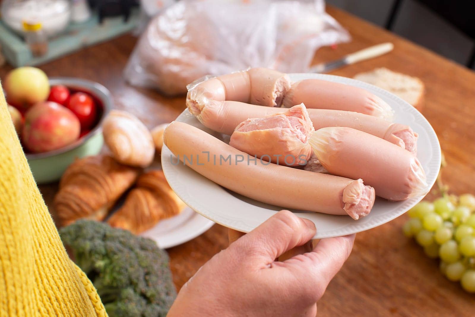 A person is holding a plate of sausages, a dish made from natural ingredients. The snap pea garnish adds a pop of color to the cuisine