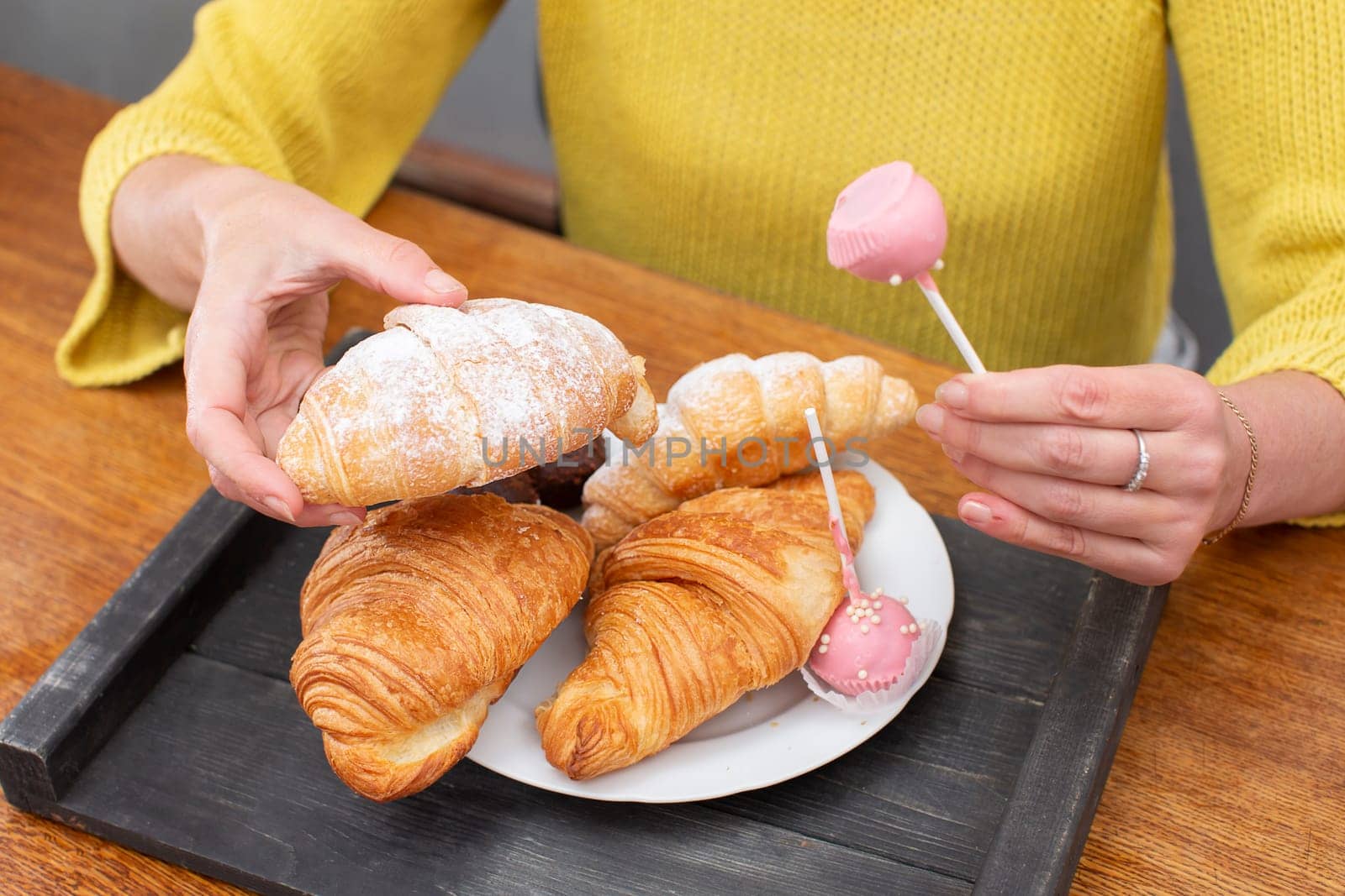 Hands hold a tray with sweets and pastries.