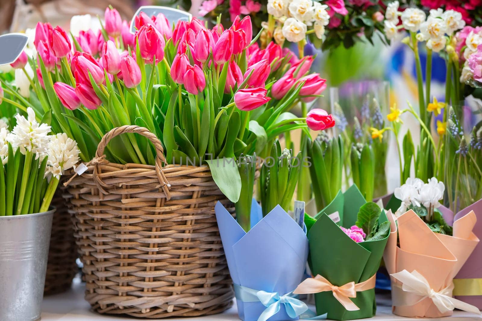 Baskets with a variety of spring flowers - tulips, phlox, begonias. Showcase of a cheerful flower shop.