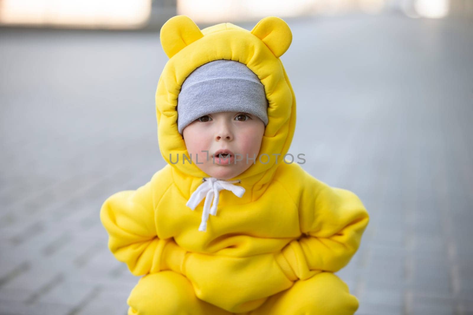 Funny little girl in a warm yellow suit with ears on a walk.