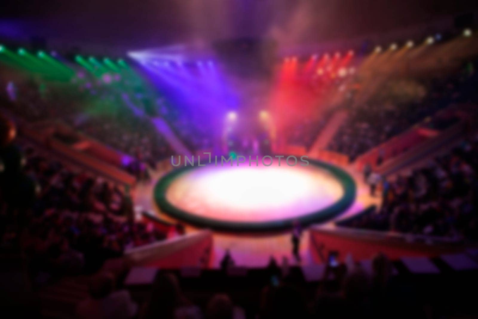 Blurred circus arena in light rays and multi-colored lights.