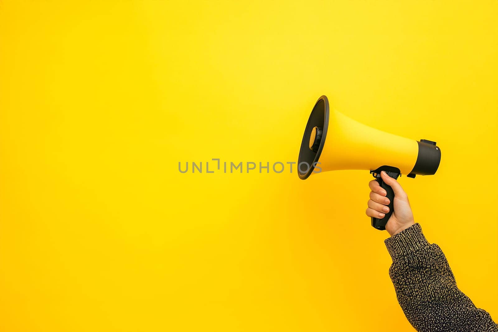 A hand holds a yellow megaphone against a vibrant yellow background, conveying a sense of energy and enthusiasm.