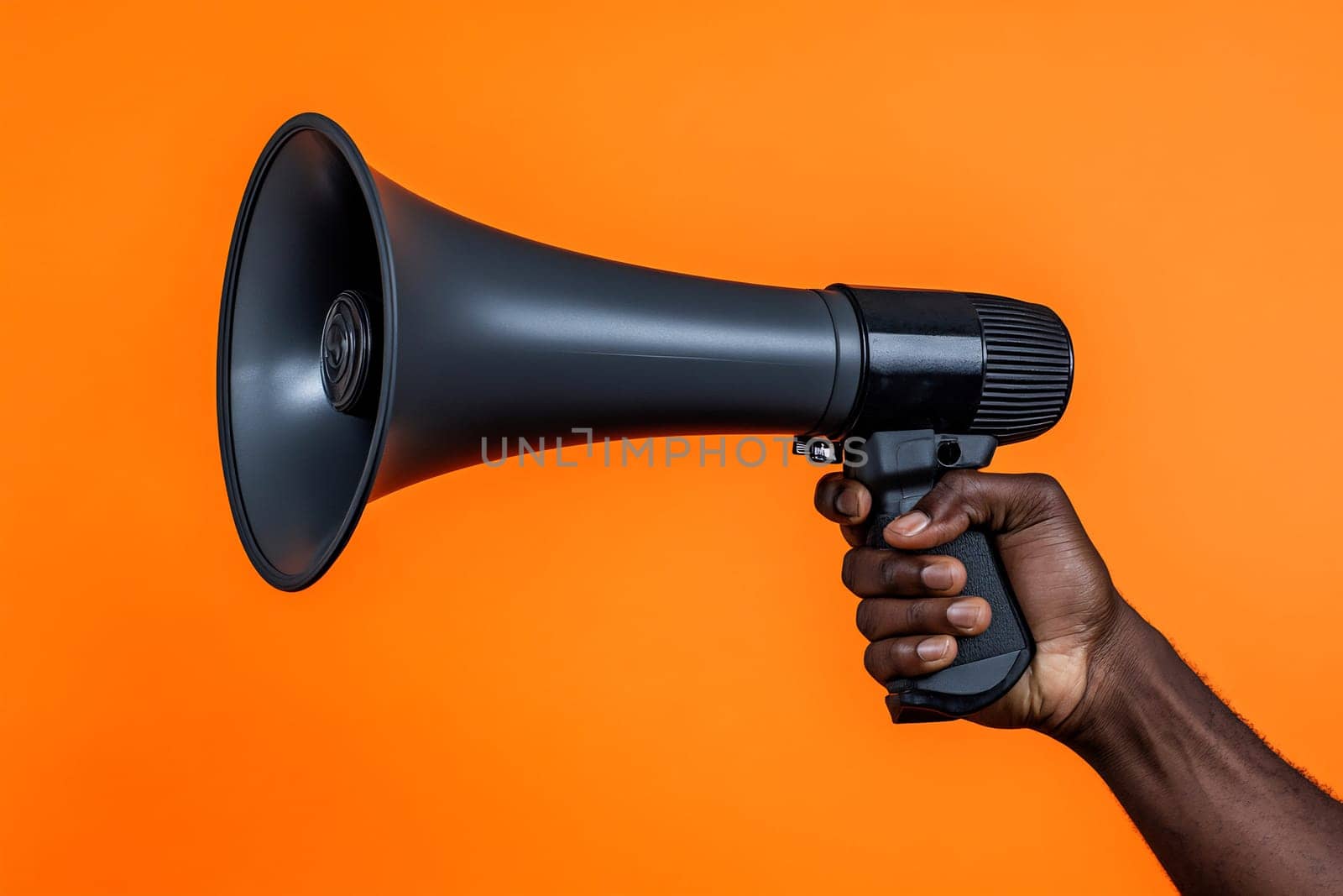 A person grips a black megaphone, ready to make an announcement, with a vivid orange backdrop enhancing the focus on the device.