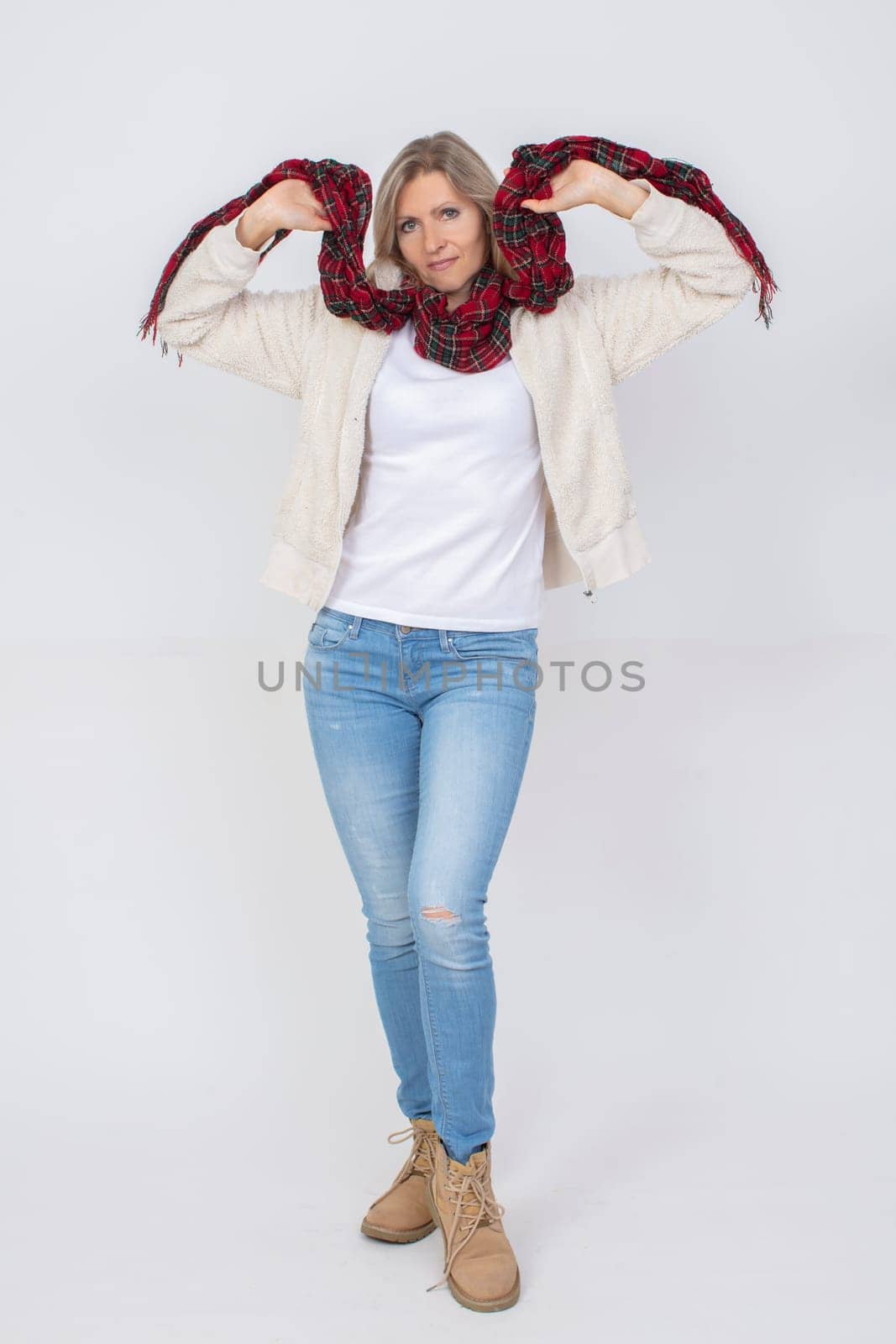 Full length beautiful adult woman wearing blue jeans and a warm sweater on a gray background.