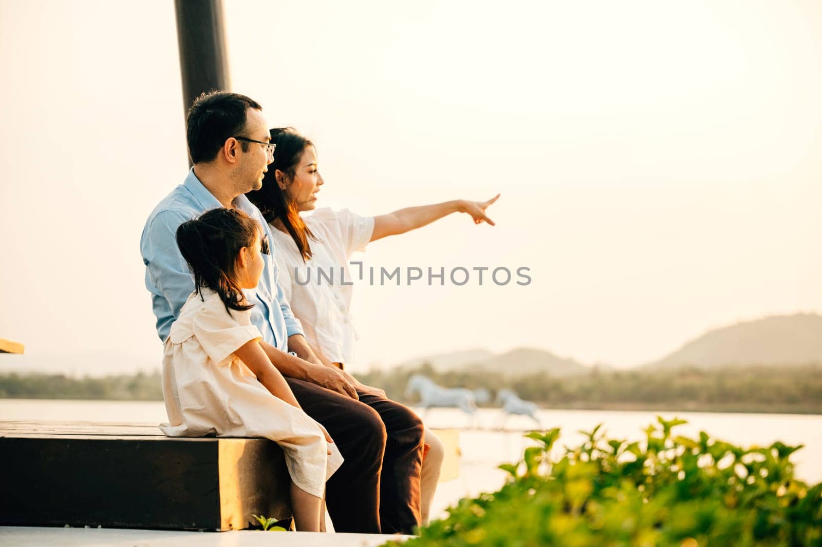 A family sitting on a bench pointing at something