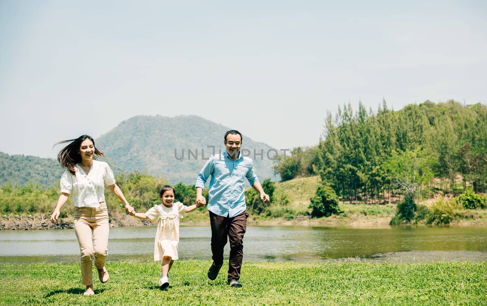 Asian family father mother and daughter holding hands and running lake in park, lifestyle parents and child kid enjoying outdoors together in nature on summer travel, Family relaxation, Front view