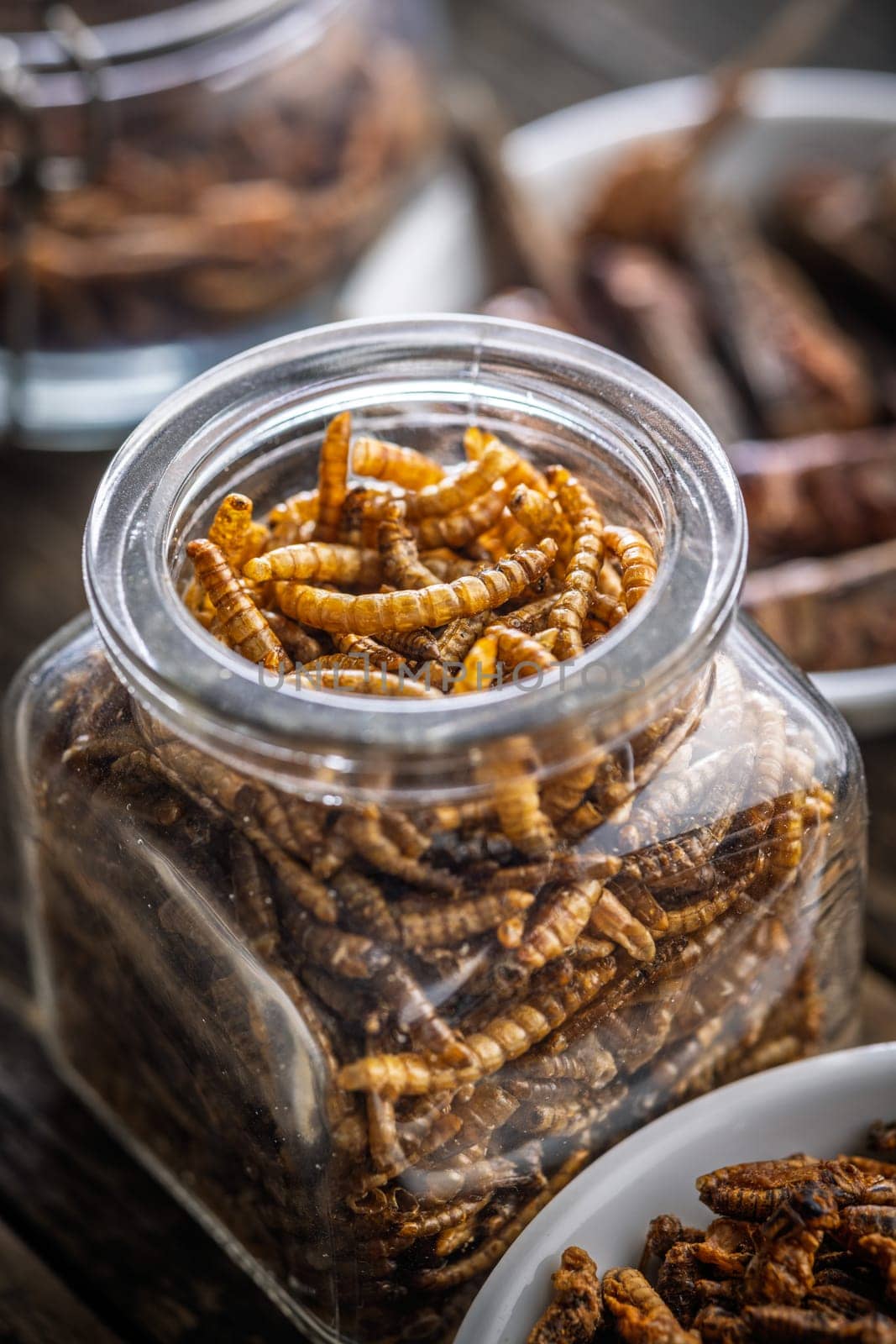 Dried salted worms. Roasted mealworms in jar on a wooden table.