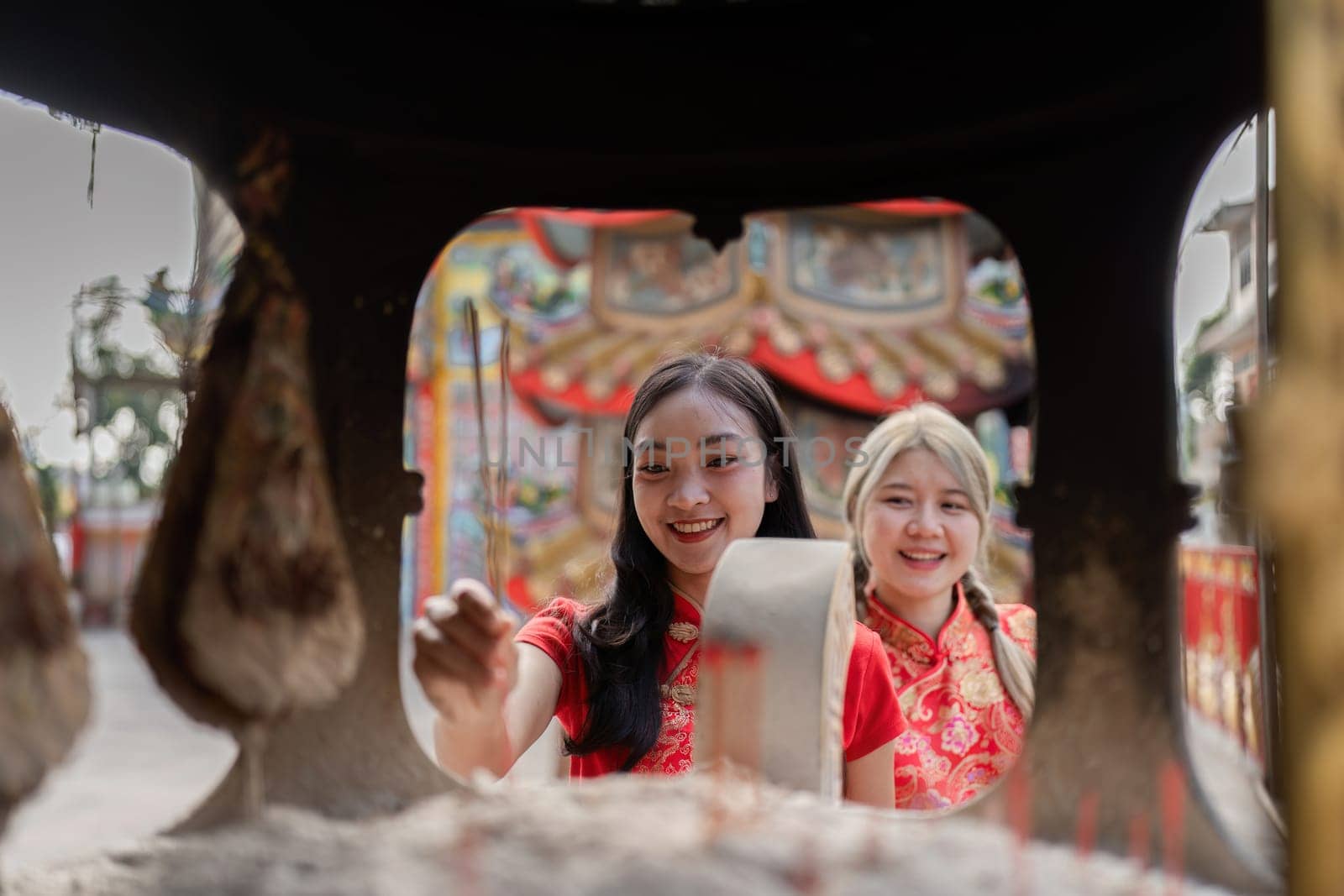Two young women celebrate Chinese New Year joyfully engaging in traditional activities in a vibrant cultural setting.