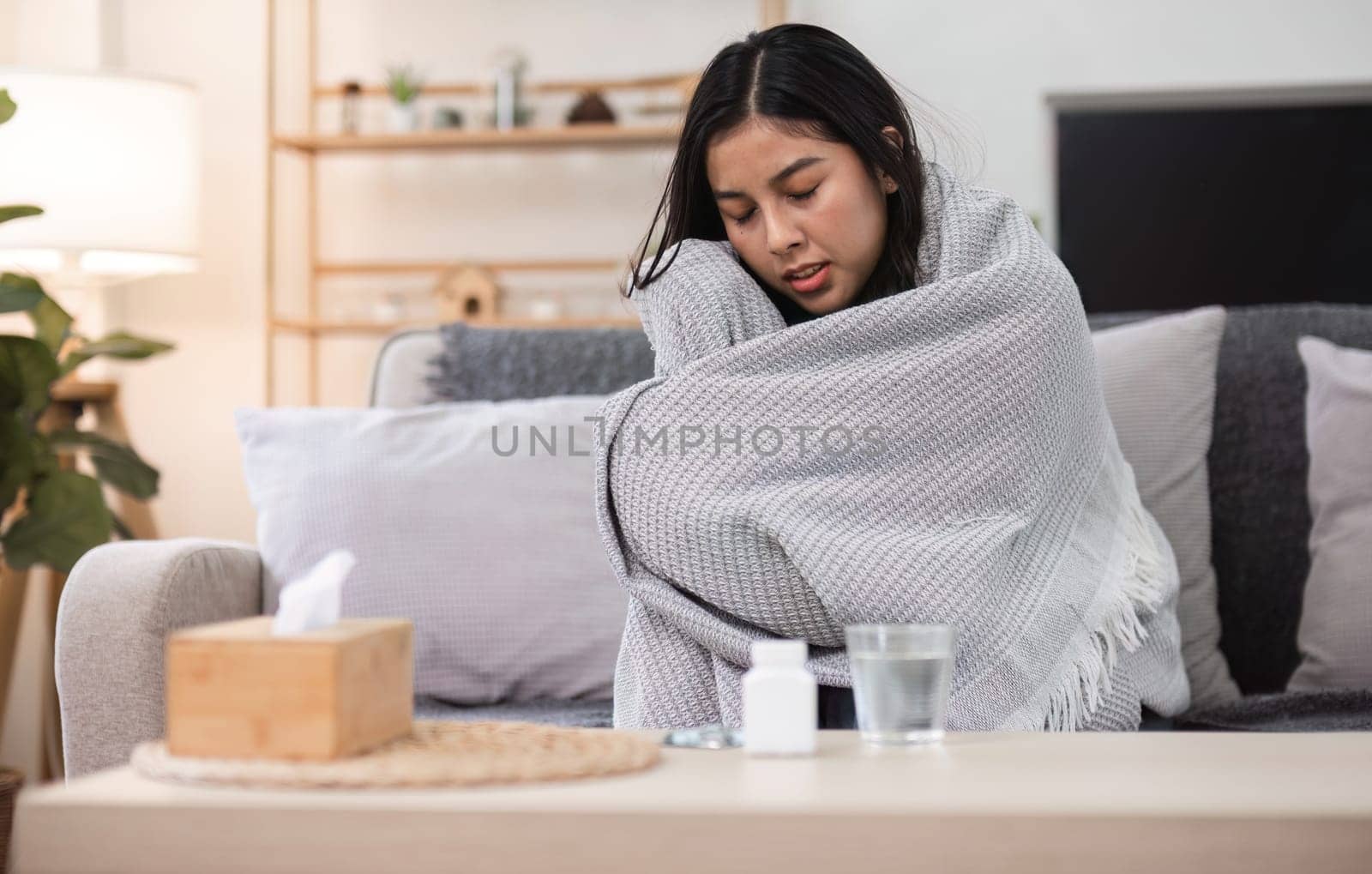 A moment of solitude as a person wraps in a blanket reflecting on feeling unwell in a cozy living room.