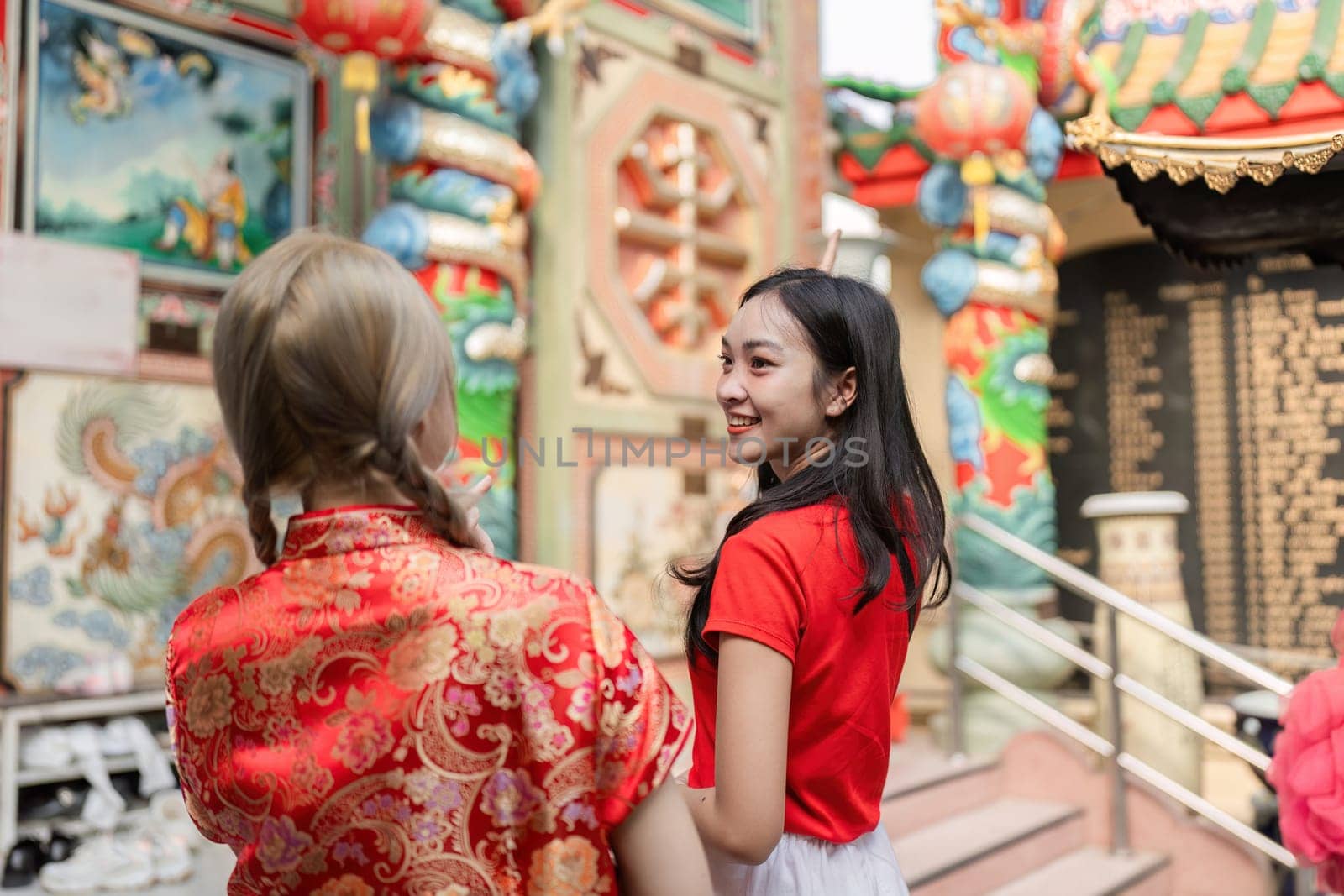 Two friends celebrate Chinese New Year enjoying vibrant decorations and festive ambiance at a lively temple.