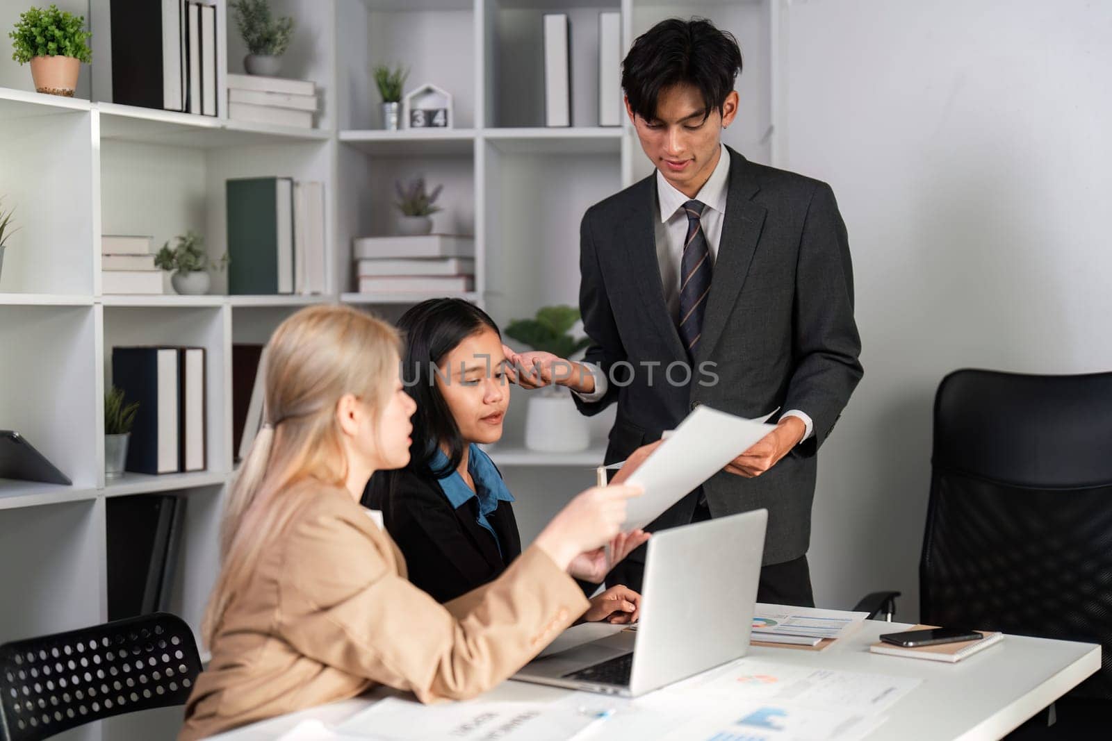 Professional business team engaged in discussion and analysis of work plans in a contemporary office environment.