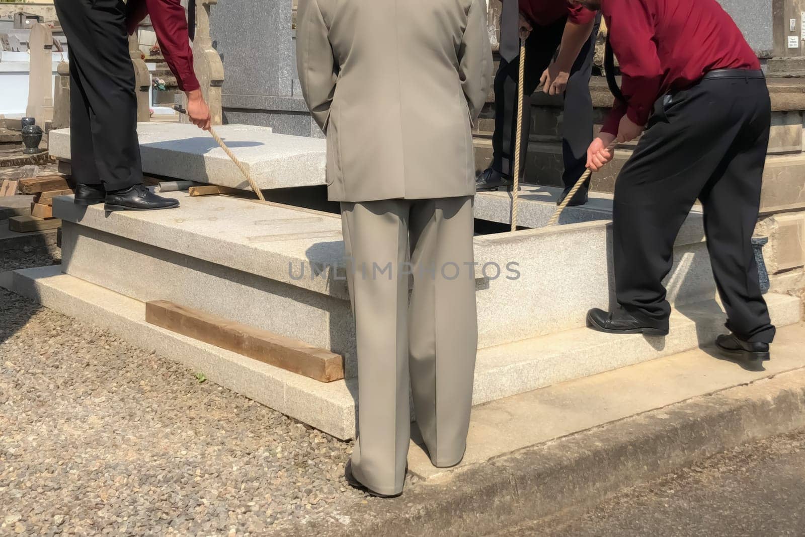 Porters lower the coffin into the grave in the cemetery