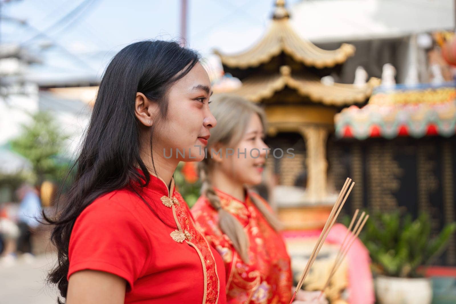 Women in traditional attire participate in Chinese New Year worship at a vibrant shrine honoring cultural traditions and faith.