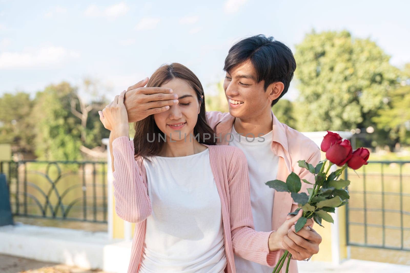 A couple shares a romantic moment celebrating love with roses in a beautiful park setting.