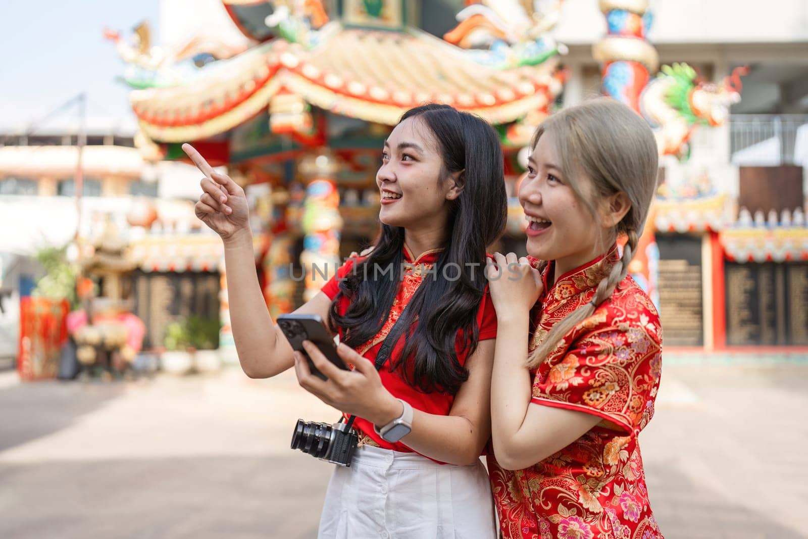 Two friends celebrate Chinese New Year at a shrine capturing joyful moments filled with worship and cultural appreciation.