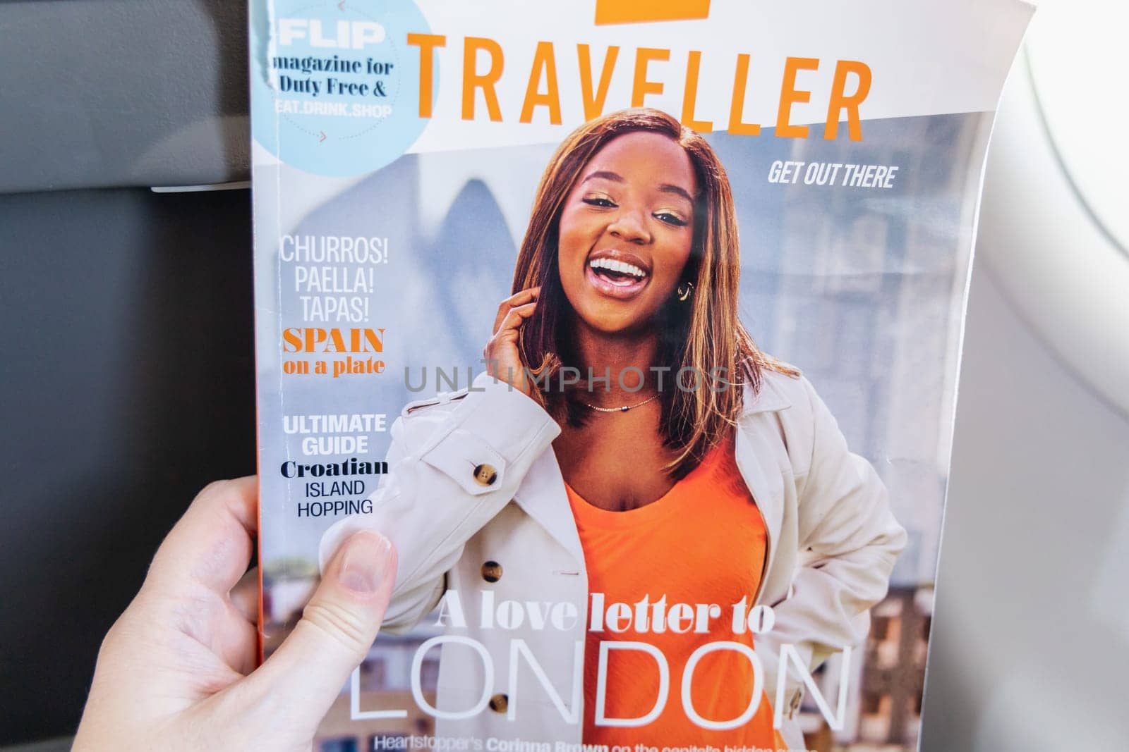 Female hands holding the magazine Traveller on board an airplane. Paris, France - January 6, 2025
