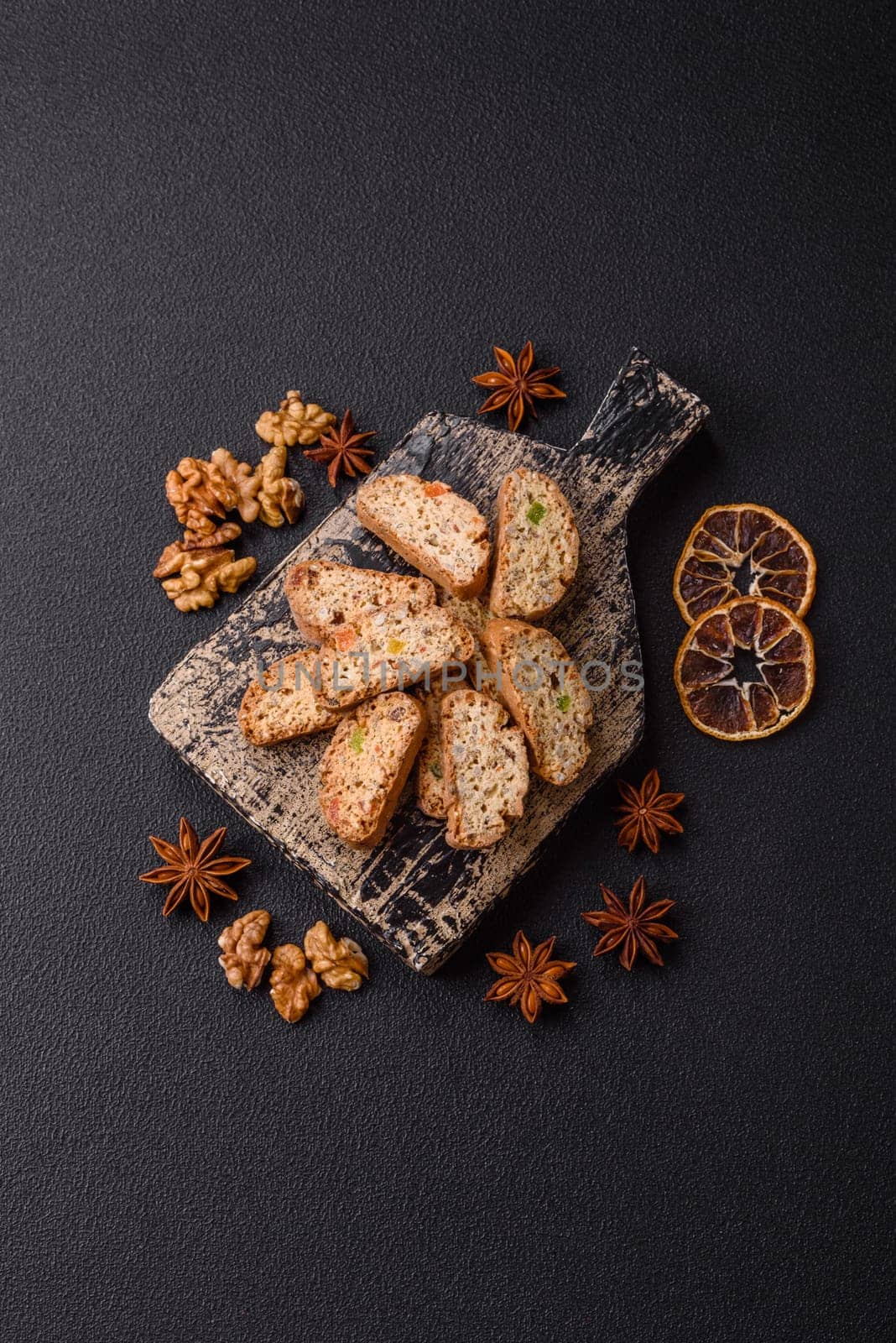 Freshly baked Italian cantuccini cookies with nuts and candied fruits on dark concrete background