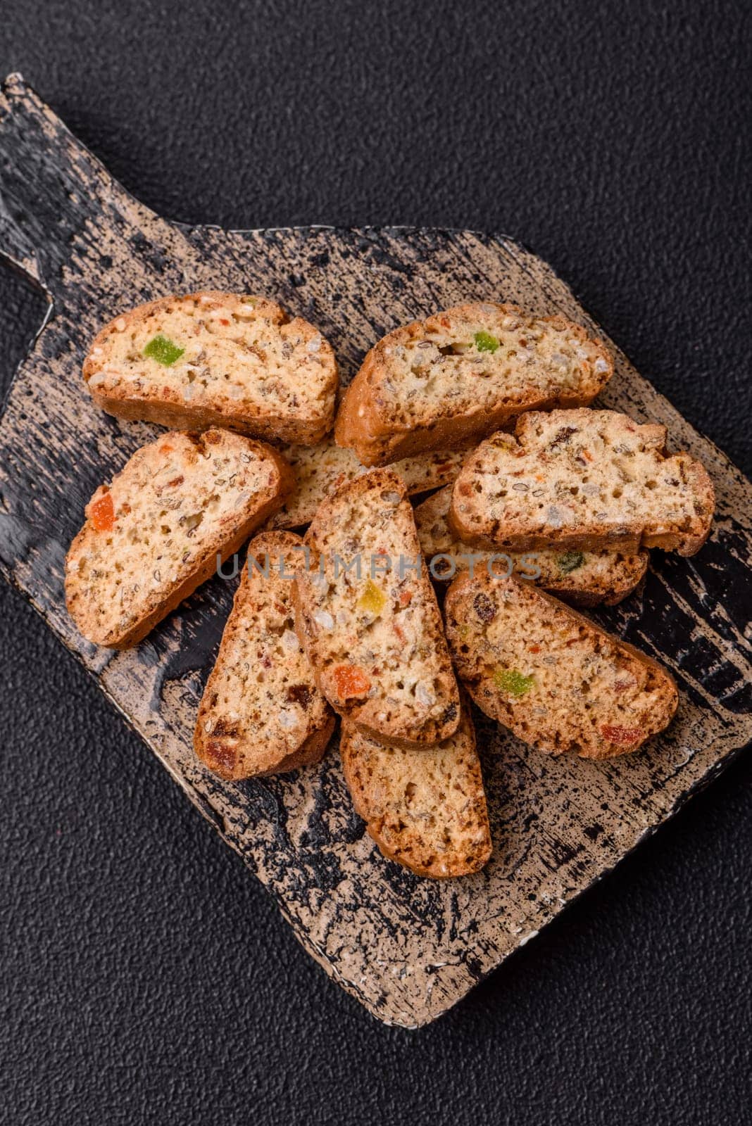 Freshly baked Italian cantuccini cookies with nuts and candied fruits on dark concrete background