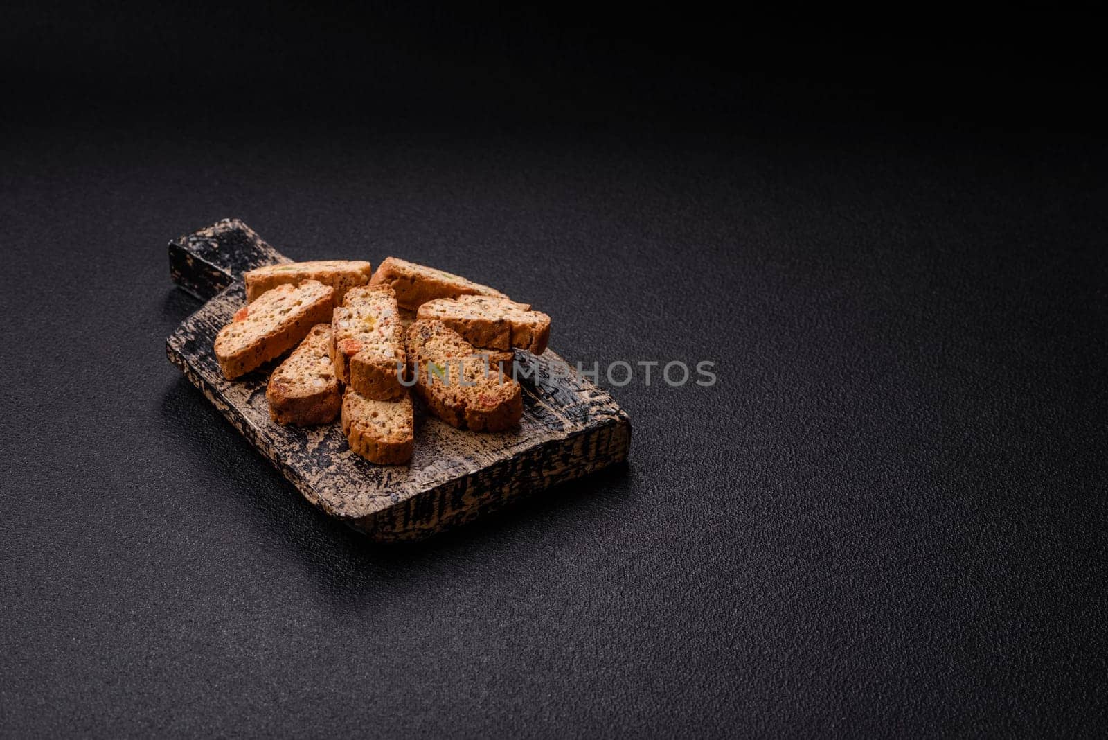 Freshly baked Italian cantuccini cookies with nuts and candied fruits on dark concrete background