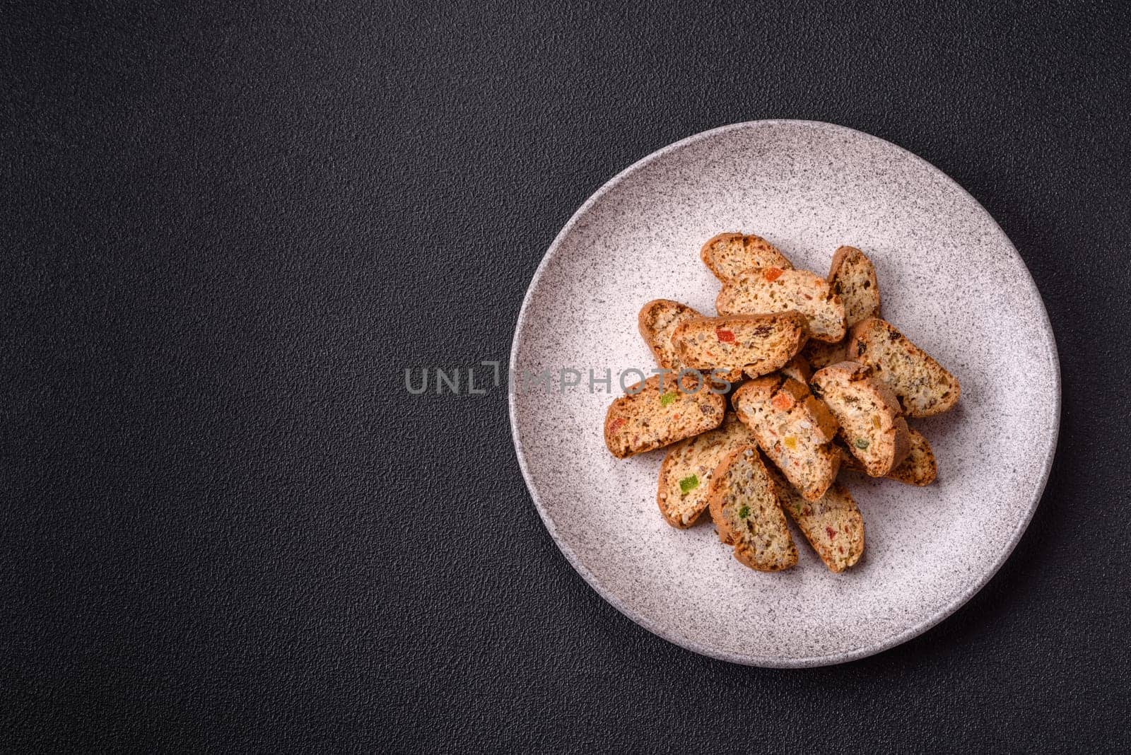 Freshly baked Italian cantuccini cookies with nuts and candied fruits on dark concrete background