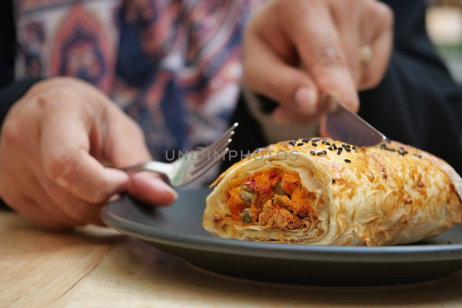 A closeup image shows someone skillfully cutting a wrap on a plate for easier eating