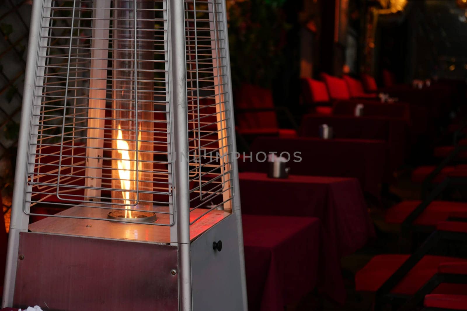 A patio heater is glowing warmly amidst empty tables, inviting a sense of comfort and warmth