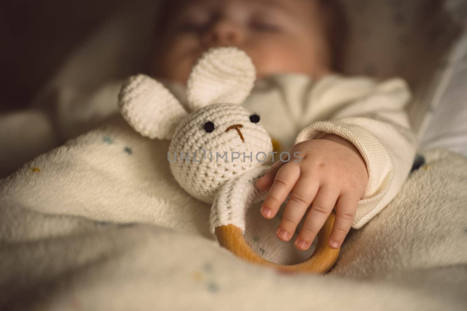 Sleeping newborn baby with a soft bunny toy under the blanket in warm, cozy sunlight. Childhood and parenting concept. High quality photo