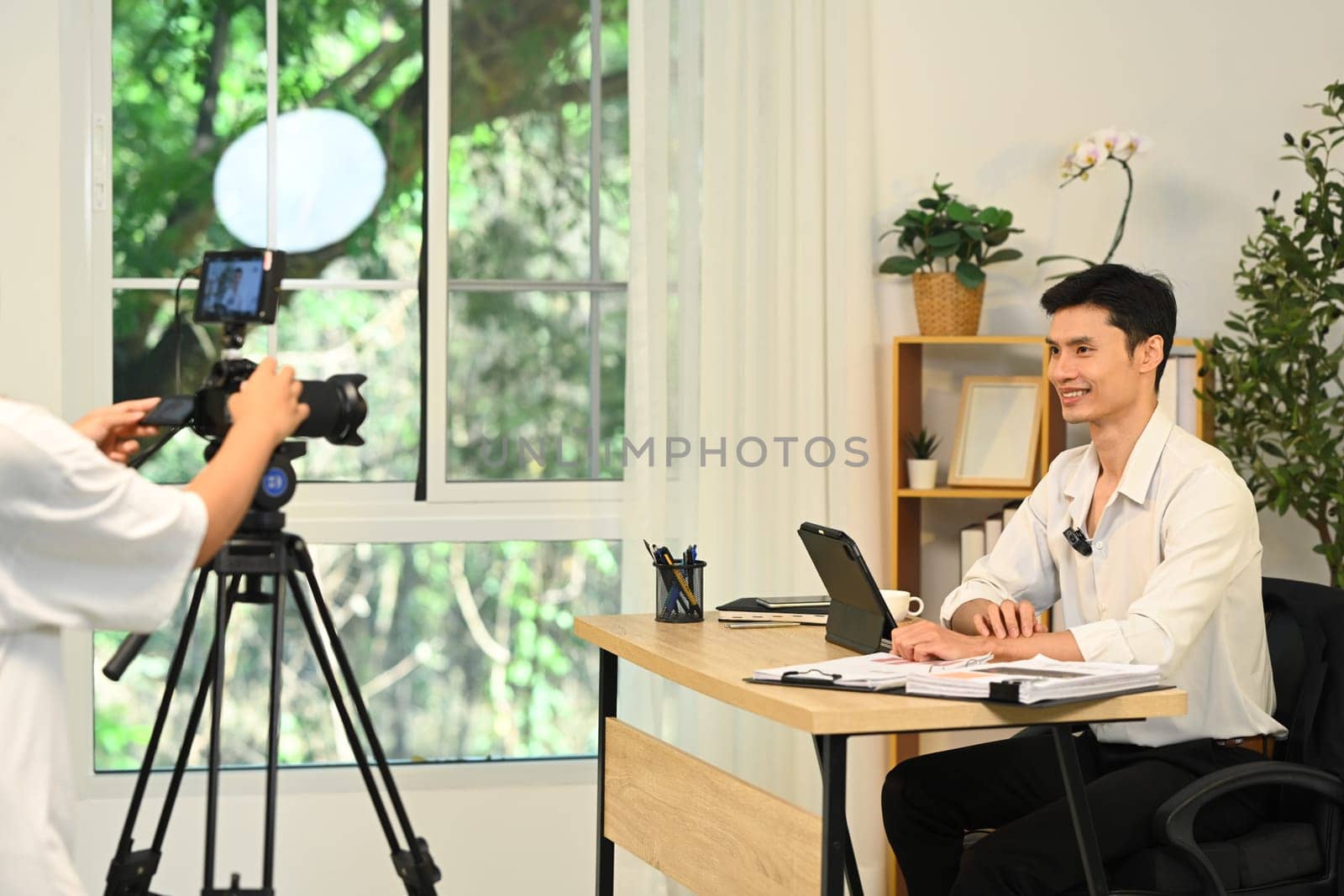 Successful millennial entrepreneur speaking on camera during office interview..