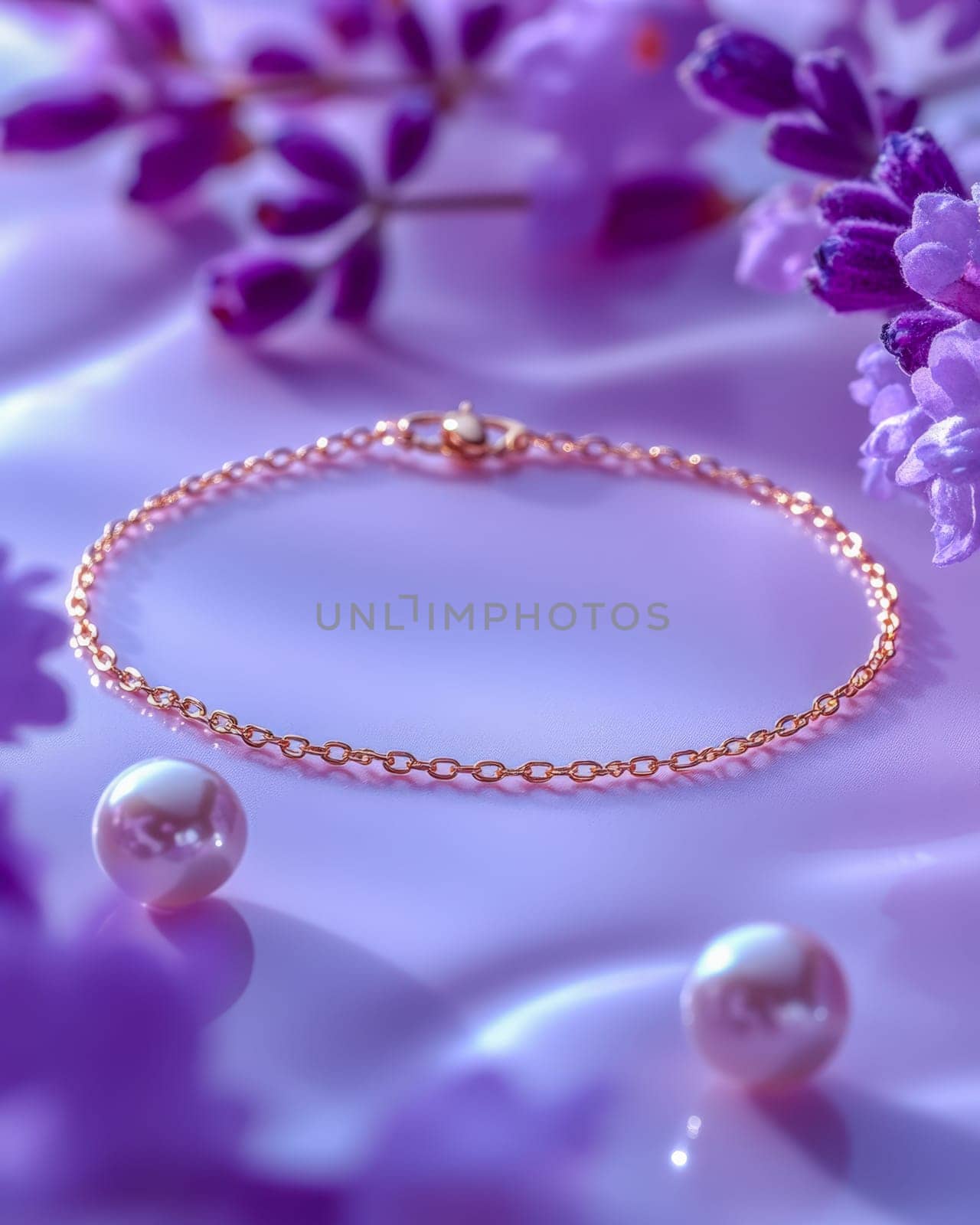 Close-up of a gold chain bracelet surrounded by purple flowers on a soft lilac background, embodying elegance and sophistication. Space for text