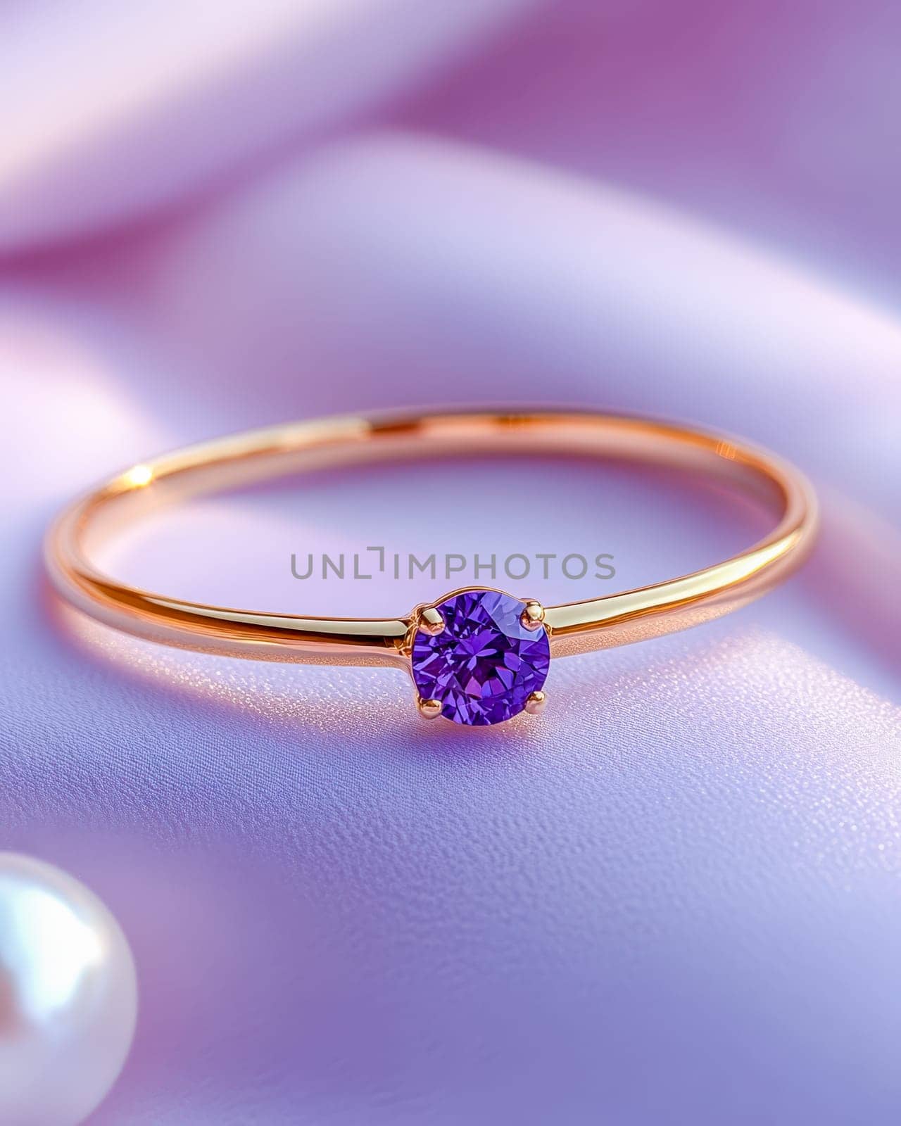 A close-up of an elegant gold ring featuring a sparkling purple gemstone, set on a soft lavender surface, representing luxury and sophistication. Space for text