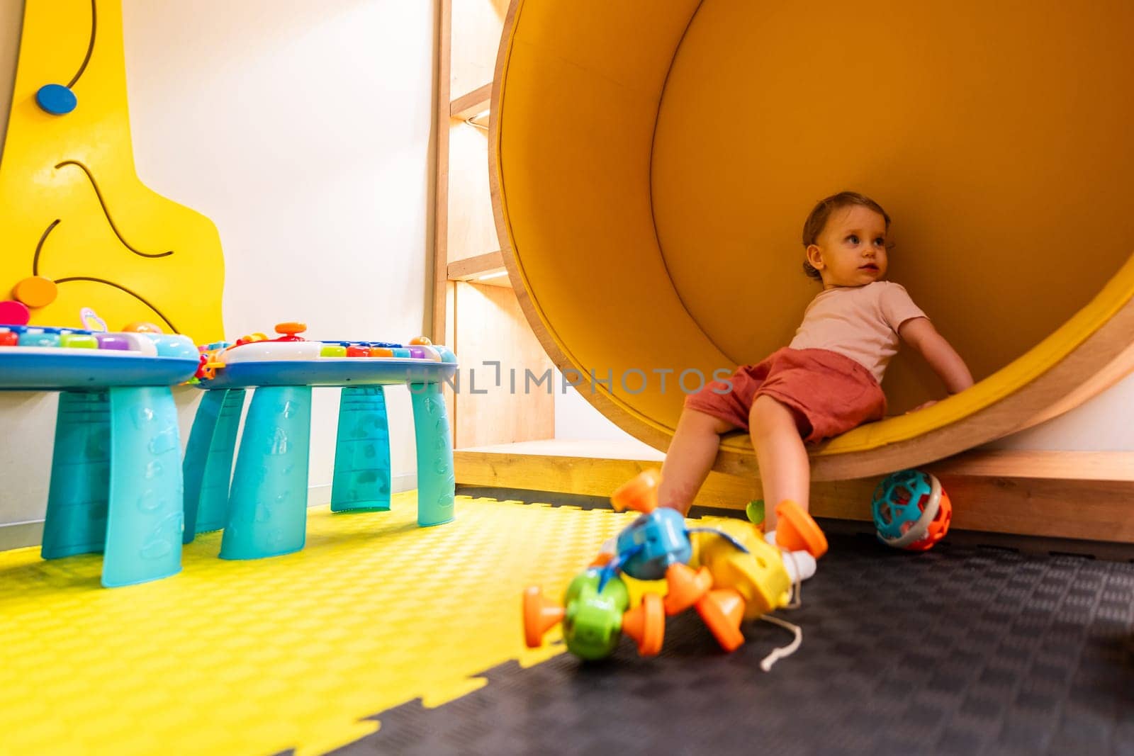 Young toddler enjoying playtime in a colorful playroom with educational toys, activity tables, and creative spaces for learning and fun