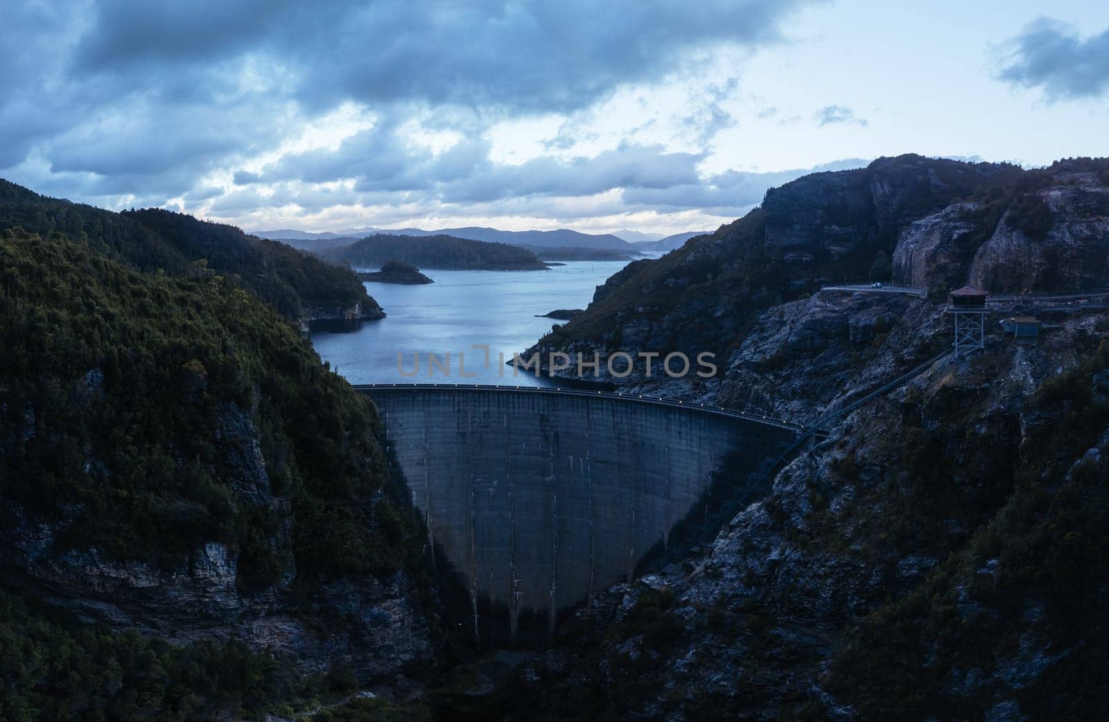 An aerial view of the Gordon Dam on a cool summer's day. It is a unique double curvature concrete arch dam with a spillway across the Gordon River near Strathgordon, South West Tasmania, Australia