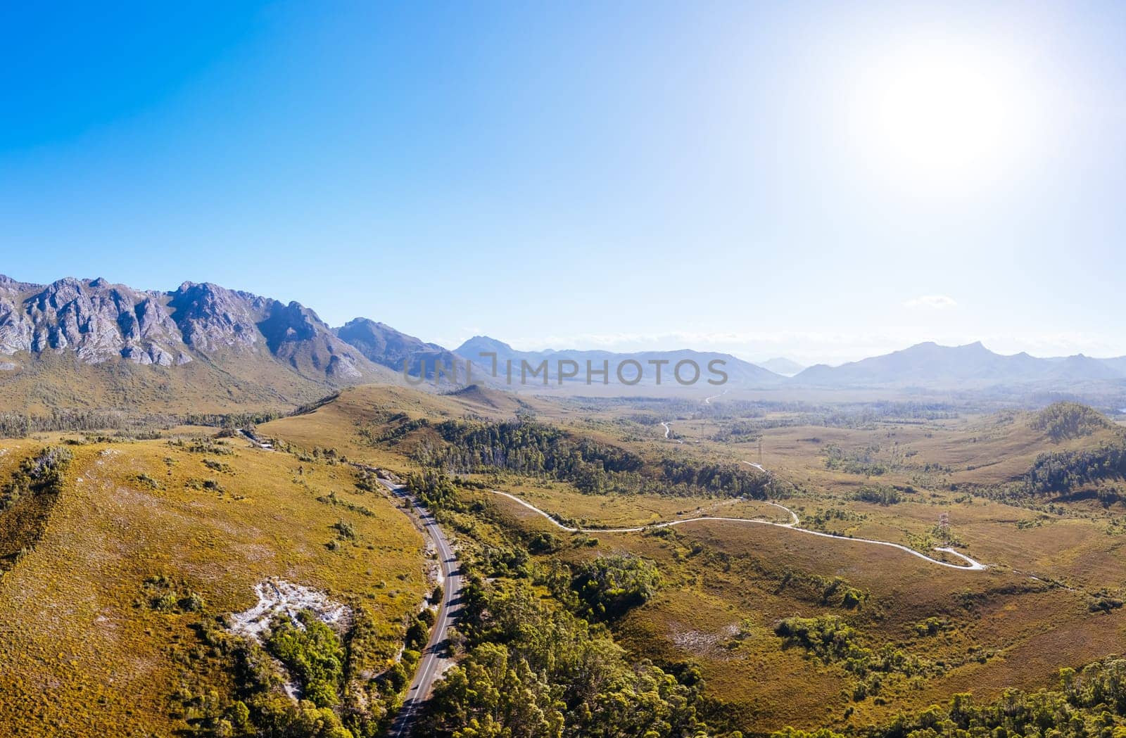 An aerial view of Gordon River Rd at the Sentinel range of mountains near Bitumen Bones Sculpture on a hot summer's afternoon in Southwest National Park, Tasmania, Australia