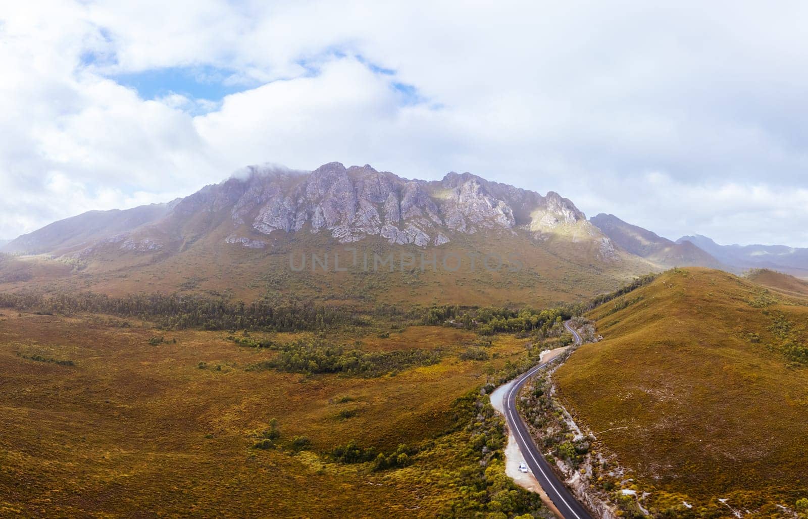 An aerial view of Gordon River Rd at the Sentinel range of mountains near Bitumen Bones Sculpture on a hot summer's afternoon in Southwest National Park, Tasmania, Australia