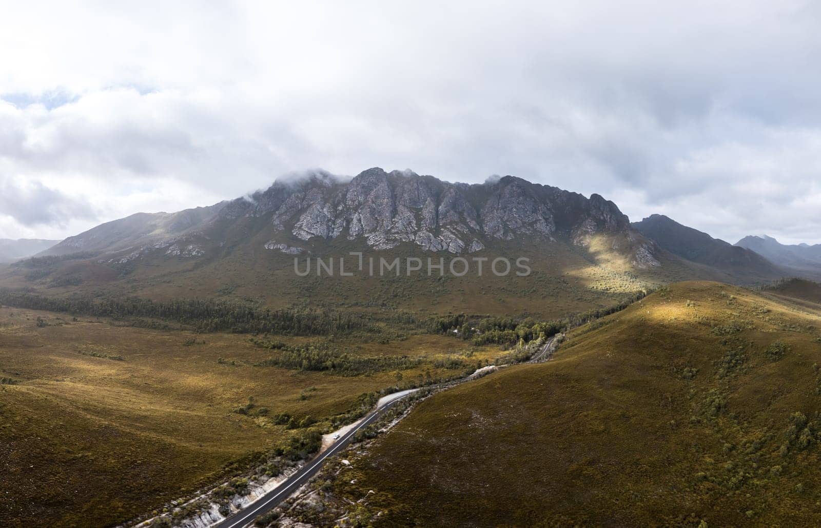 An aerial view of Gordon River Rd at the Sentinel range of mountains near Bitumen Bones Sculpture on a hot summer's afternoon in Southwest National Park, Tasmania, Australia