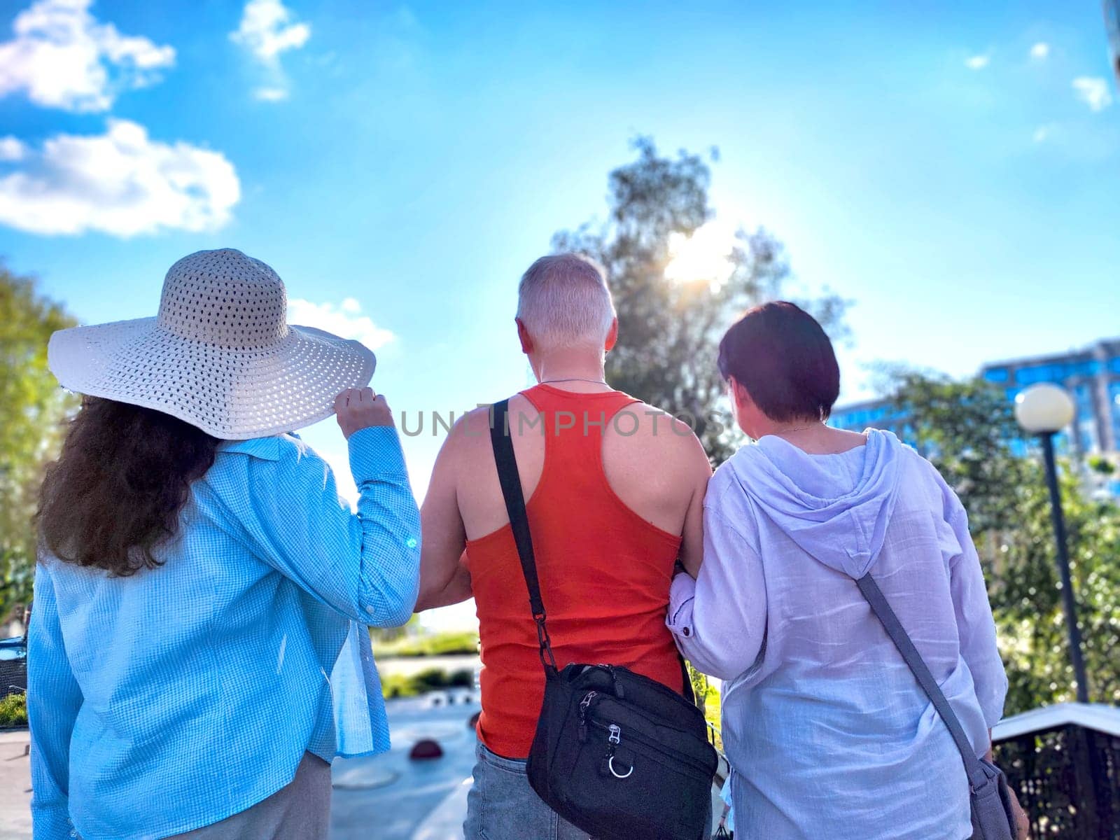 Friends walk together in park, enjoying the warm sun and vibrant summer atmosphere on a clear day