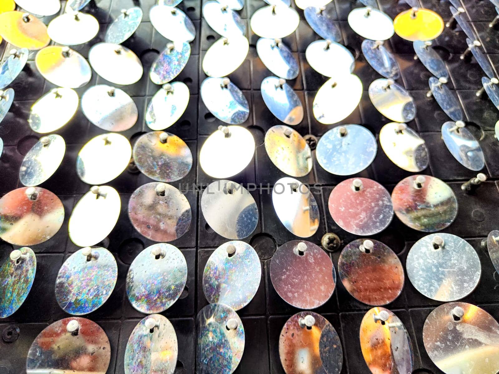 Shiny metal discs are neatly organized, creating a mesmerizing texture and pattern ideal for backgrounds or display areas.